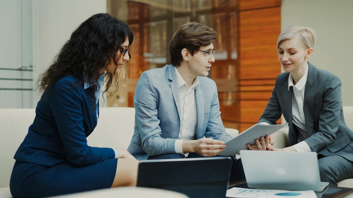 Three professionals discuss documents at a table